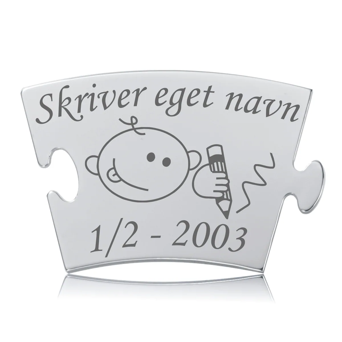 Skinnende Memozz Classic brik med gravering af et barn, der skriver. Teksten "Skriver eget navn" og en dato er tydelig.