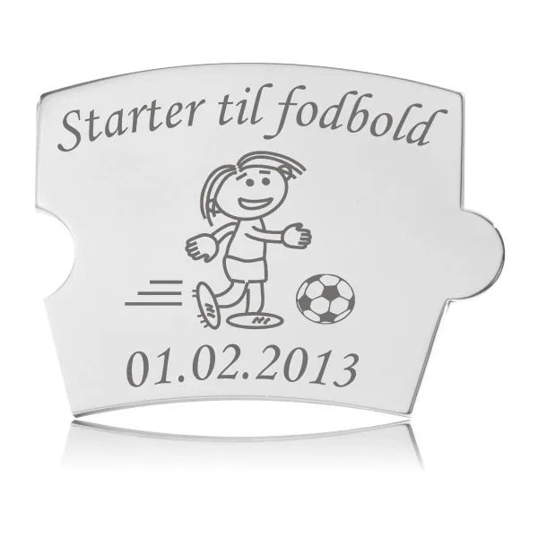 Memozz Spin brik i poleret rustfrit stål med gravering af en pige, der spiller fodbold, og teksten "Starter til fodbold".