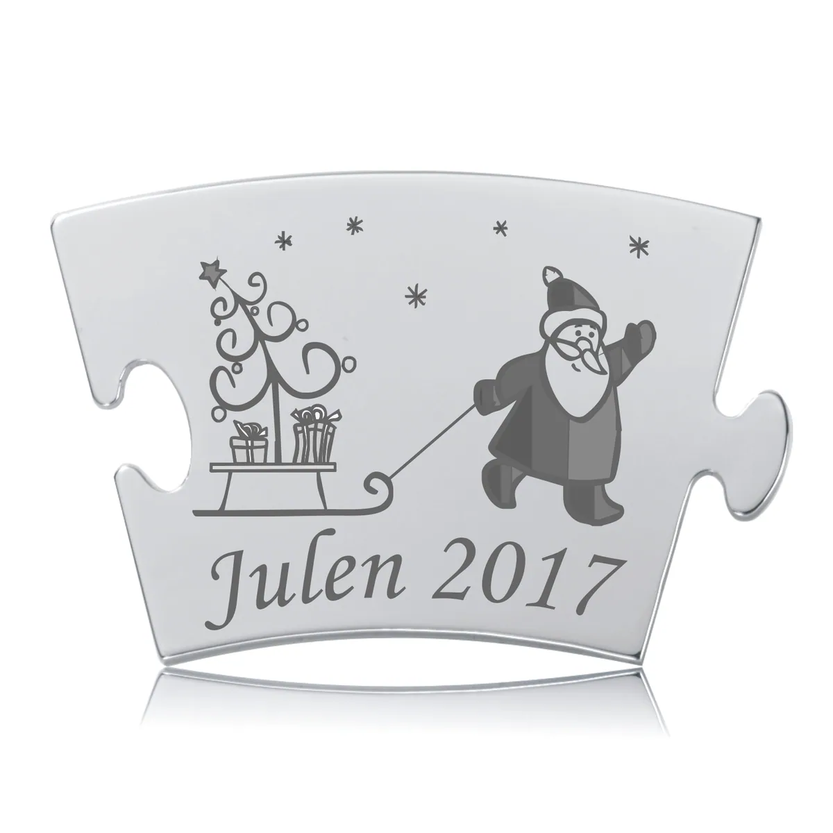 Årets Julebrik 2017 – Puzzlebrik i stål med gravering af julemand, kane og træ. "Julen 2017" står smukt graveret.