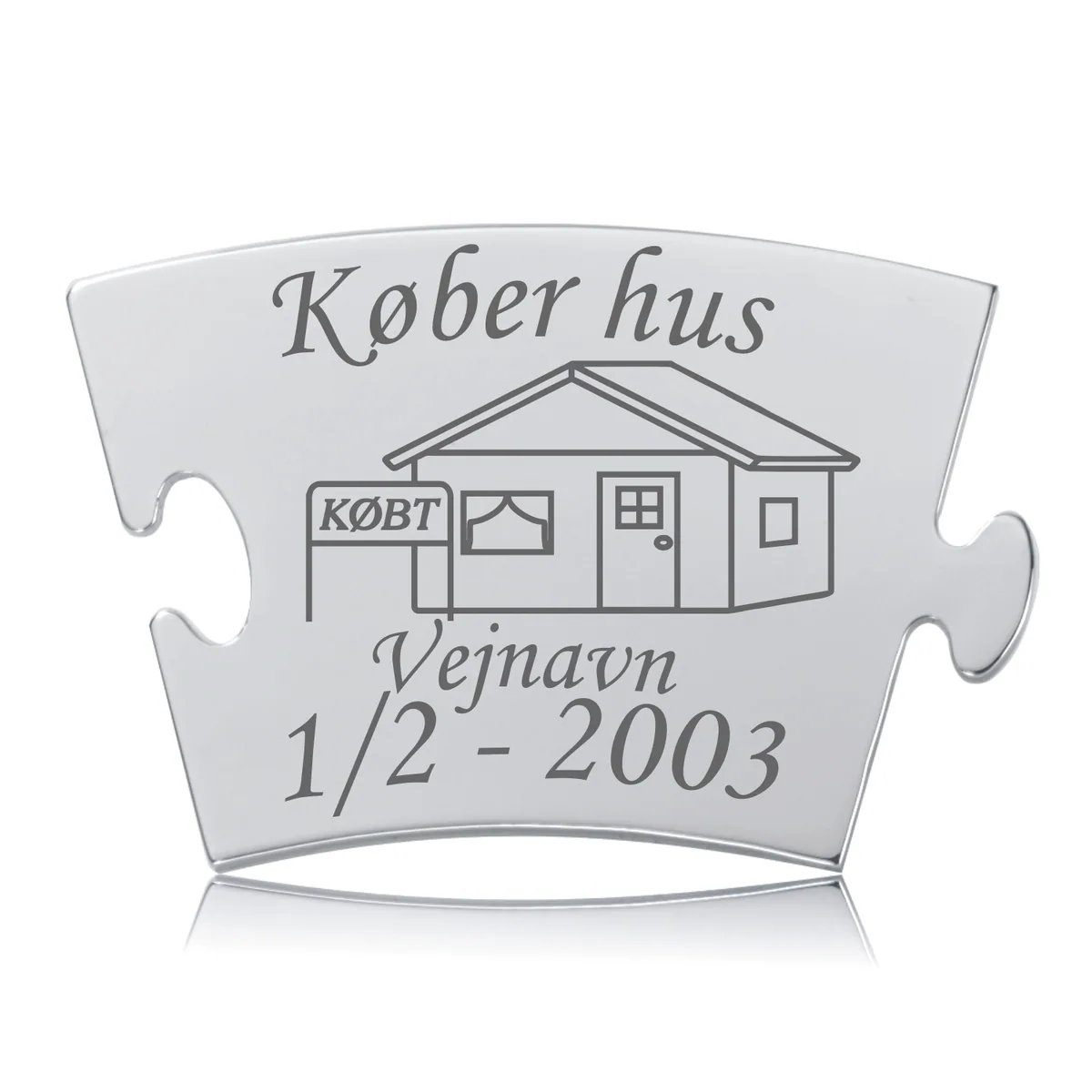 Memozz Classic brik "Køber hus" i håndpoleret rustfri stål med detaljeret lasergravering af et hus og teksten "Køber hus".