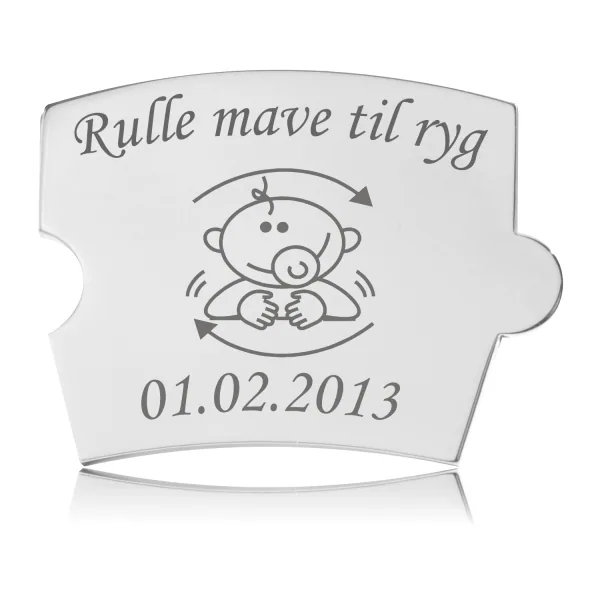 Memozz Spin brik i poleret stål med illustration af baby der ruller og teksten "Rulle mave til ryg"