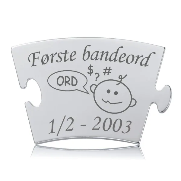 Memozz Classic brik "Første bandeord" i håndpoleret rustfri stål med mørk lasergravering, illustreret med et barn og en taleboble.