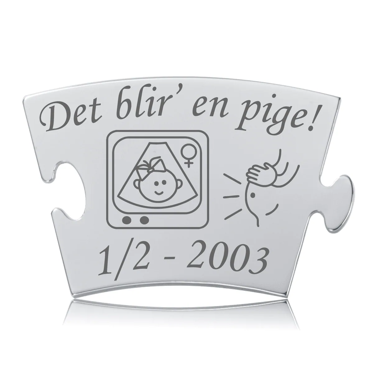 Blankpoleret Memozz Classic stålbrik med gravering: "Det blir' en pige!" og ultralydsbillede af glad baby med sløjfe, kønssymbol og mave.