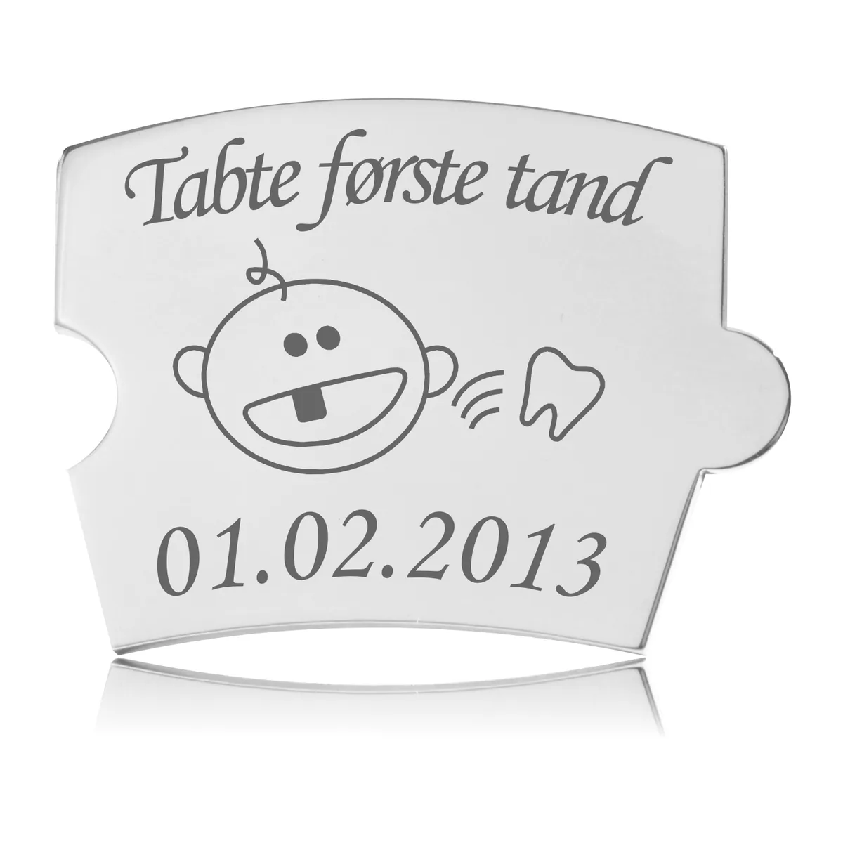 Memozz Spin brik i stål med gravering for 'Tabte første tand'. Motivet viser en glad baby med en manglende tand.