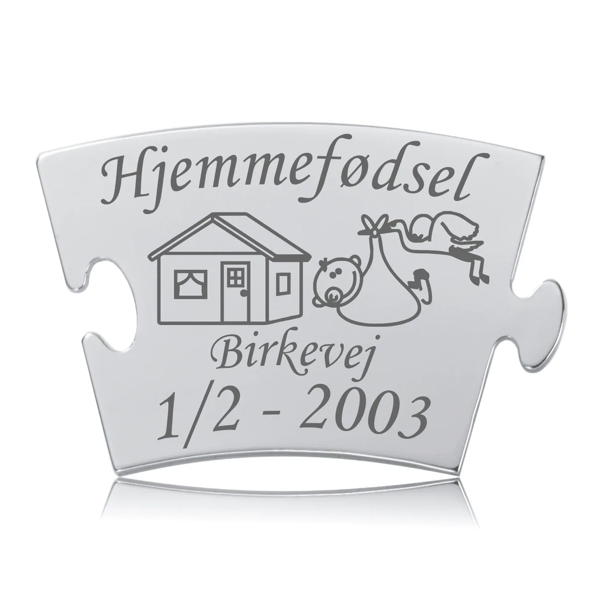 Memozz Classic mindebrik med teksten "Hjemmefødsel", et hus og en stork, udført i mørk lasergravering på skinnende rustfrit stål.