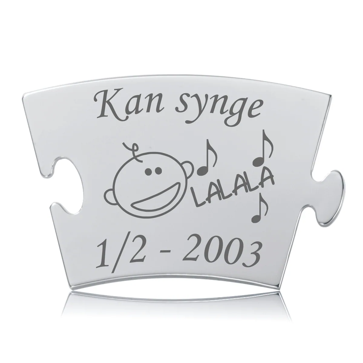 Memozz Classic brik "Kan synge" i blankpoleret stål med lasergravering af en glad figur og musiknoder.