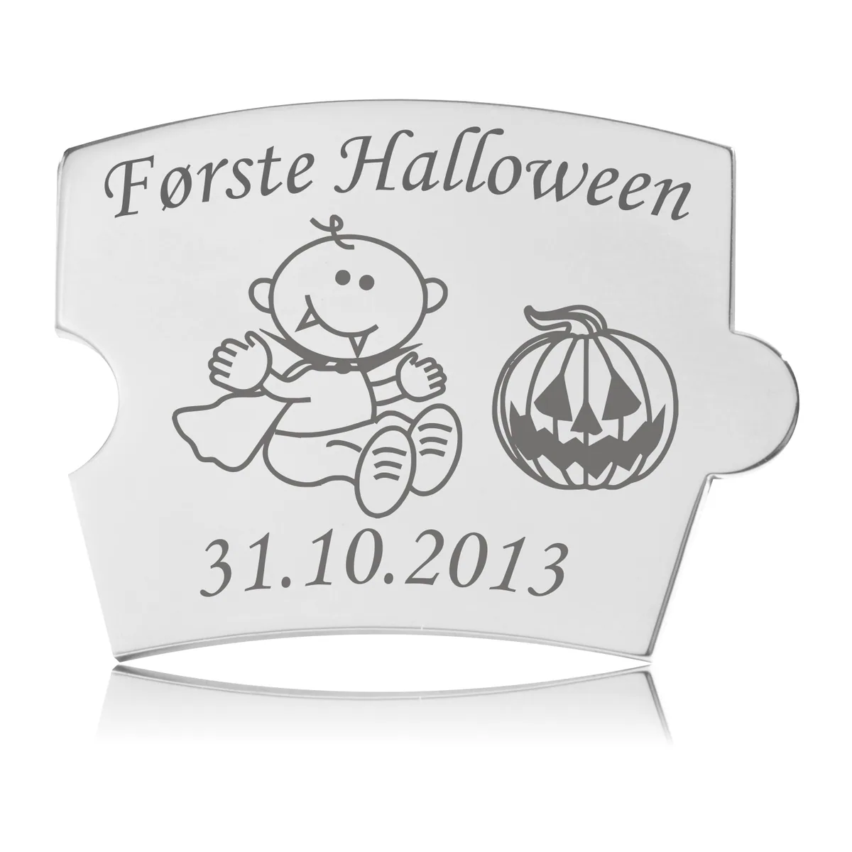 Memozz Spin brik i håndpoleret rustfrit stål med lasergraveret motiv af baby i vampyrdragt og græskar, samt teksten "Første Halloween".