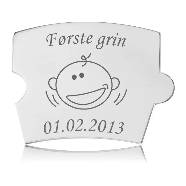 Memozz Spin brik "Første grin" i blankt, håndpoleret rustfrit stål med graveret babyansigt og inskription.
