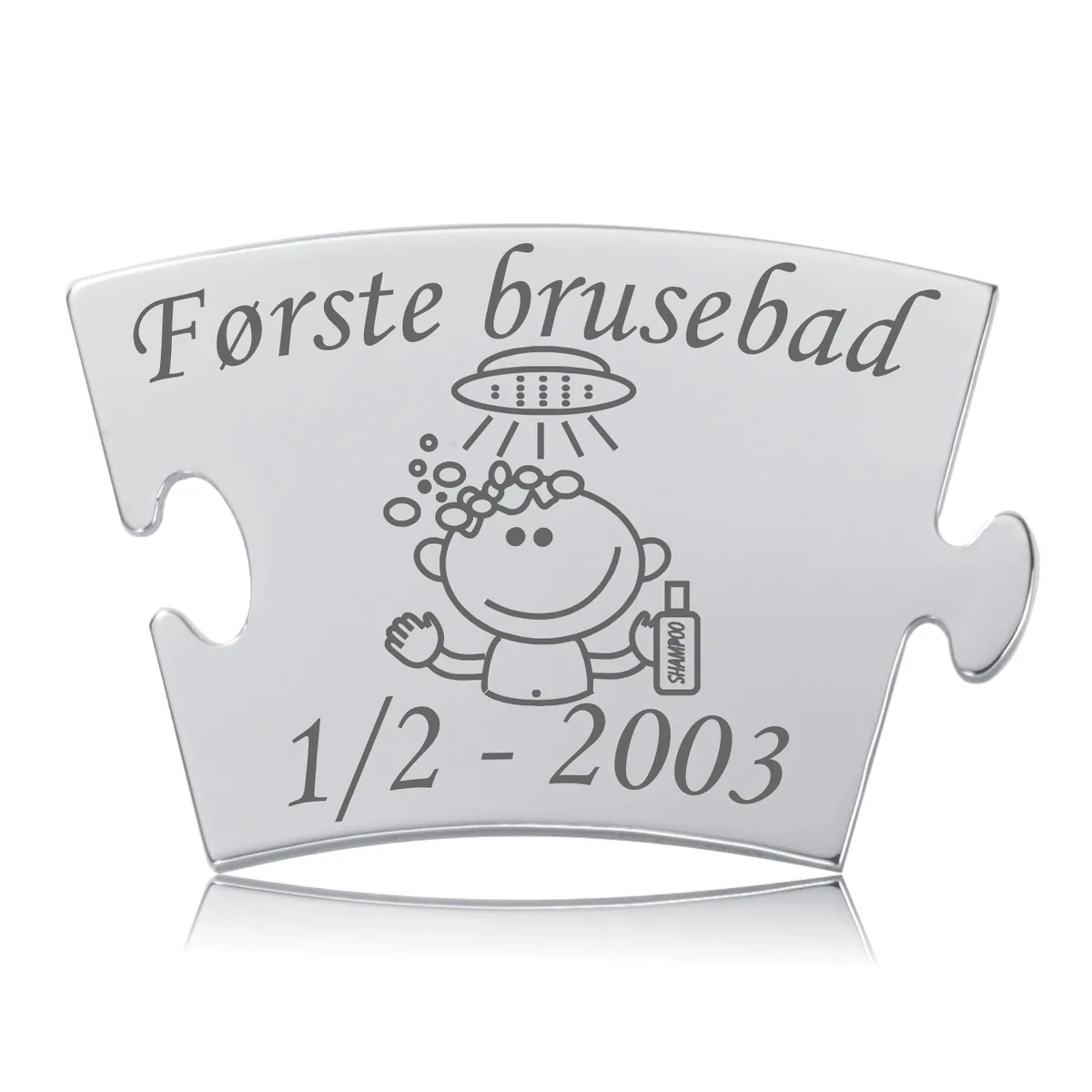 Memozz Classic brik i rustfrit stål med gravering af et barn under bruser, teksten "Første brusebad" og dato