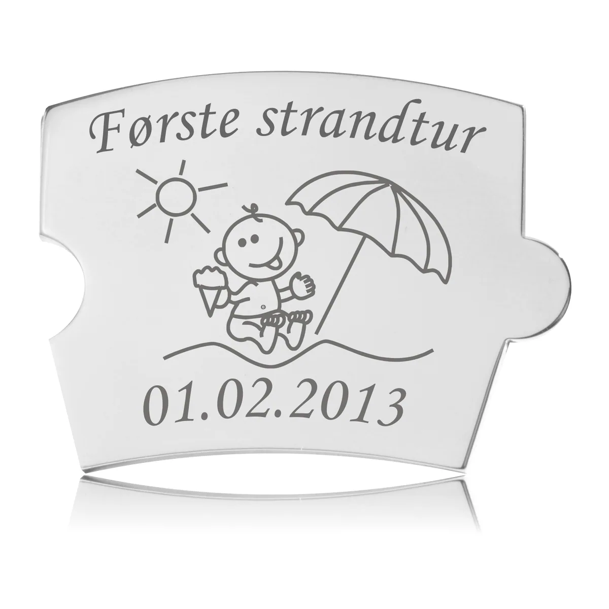 Memozz Spin brik "Første strandtur" i poleret rustfrit stål med lasergraveret motiv af baby på strand med is, sol og parasol.