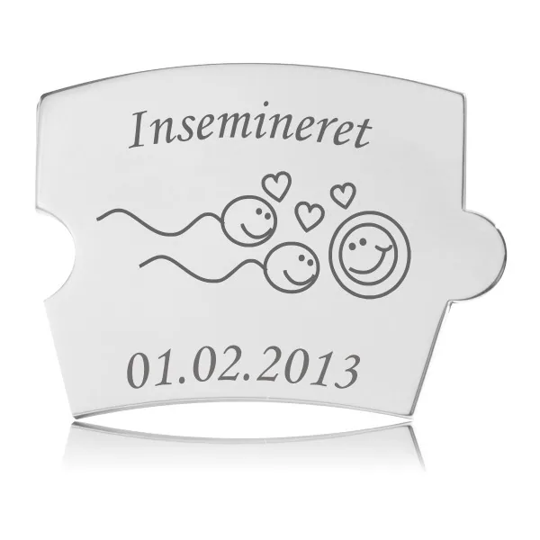 Blank, håndpoleret Memozz Spin "Insemineret" brik i rustfrit stål med gravering af glade sædceller og en ægcelle, der symboliserer befrugtning