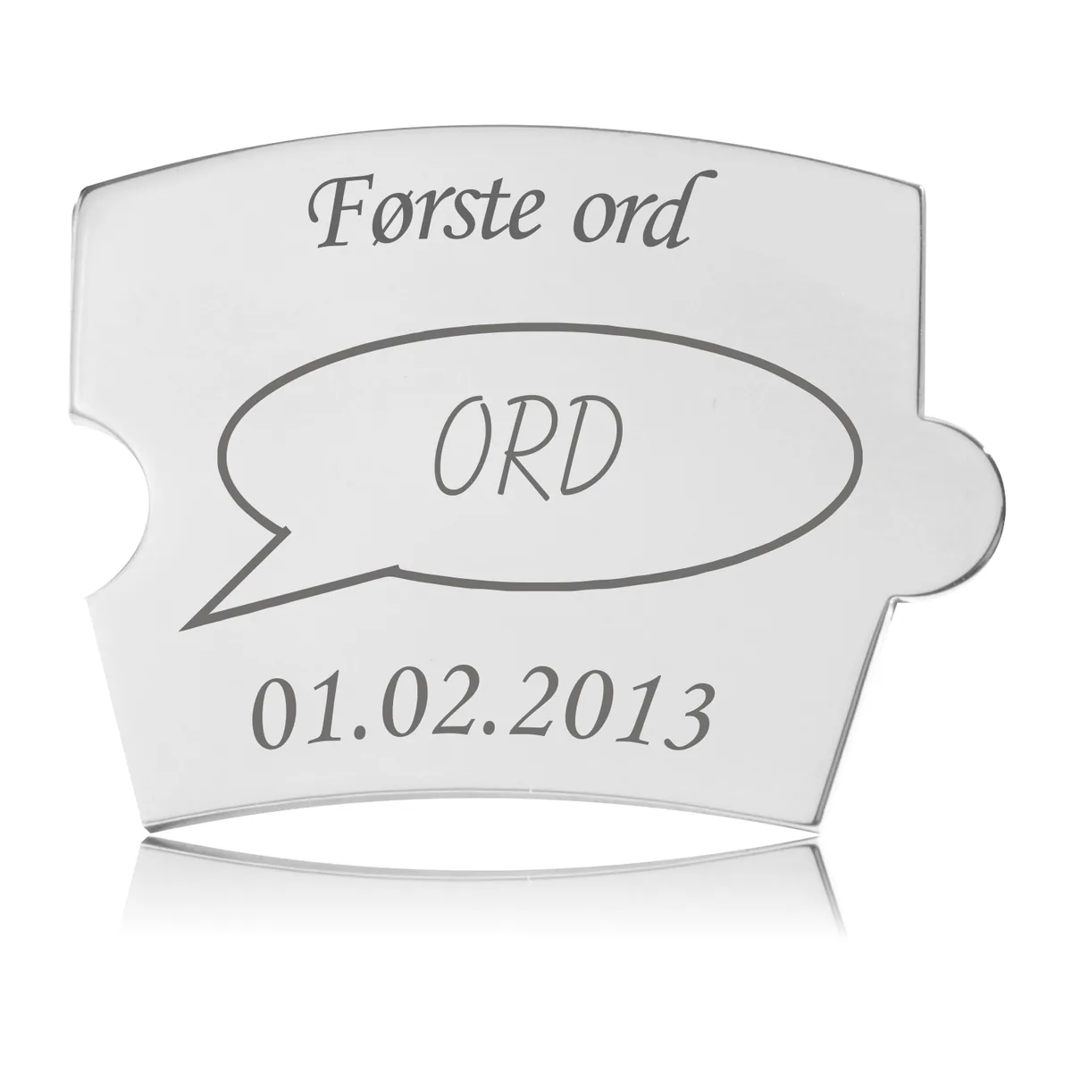 Memozz Spin brik i rustfrit stål med teksten "Første ord" og en tankeboble med "ORD" graveret
