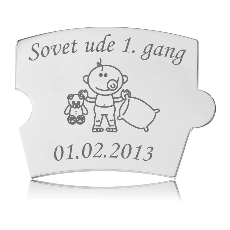 Memozz Spin brik i håndpoleret rustfrit stål med teksten "Sovet ude 1. gang" og et stregtegnet barn med bamse og pude