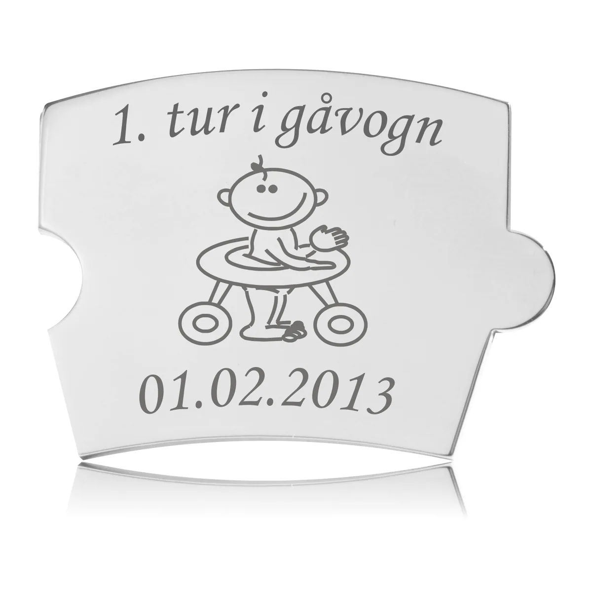 Memozz Spin brik i håndpoleret rustfrit stål med gravering af en baby i gåvogn og teksten "1. tur i gåvogn".