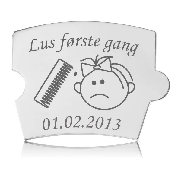 Memozz Spin brik i håndpoleret rustfrit stål med gravering "Lus første gang" og illustration af en lusekam og ked af det ansigt. Datoen 01.02.2013 er også synlig.