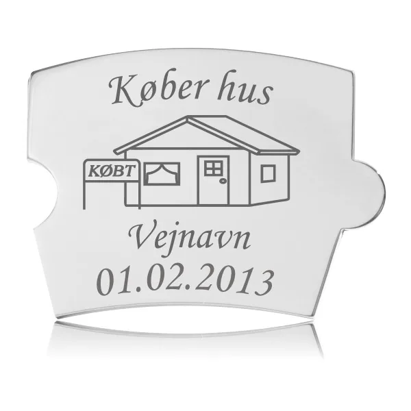 Memozz Spin brik "Køber hus" i håndpoleret rustfrit stål med husmotiv og "Købt" skilt graveret i mørkegrå.